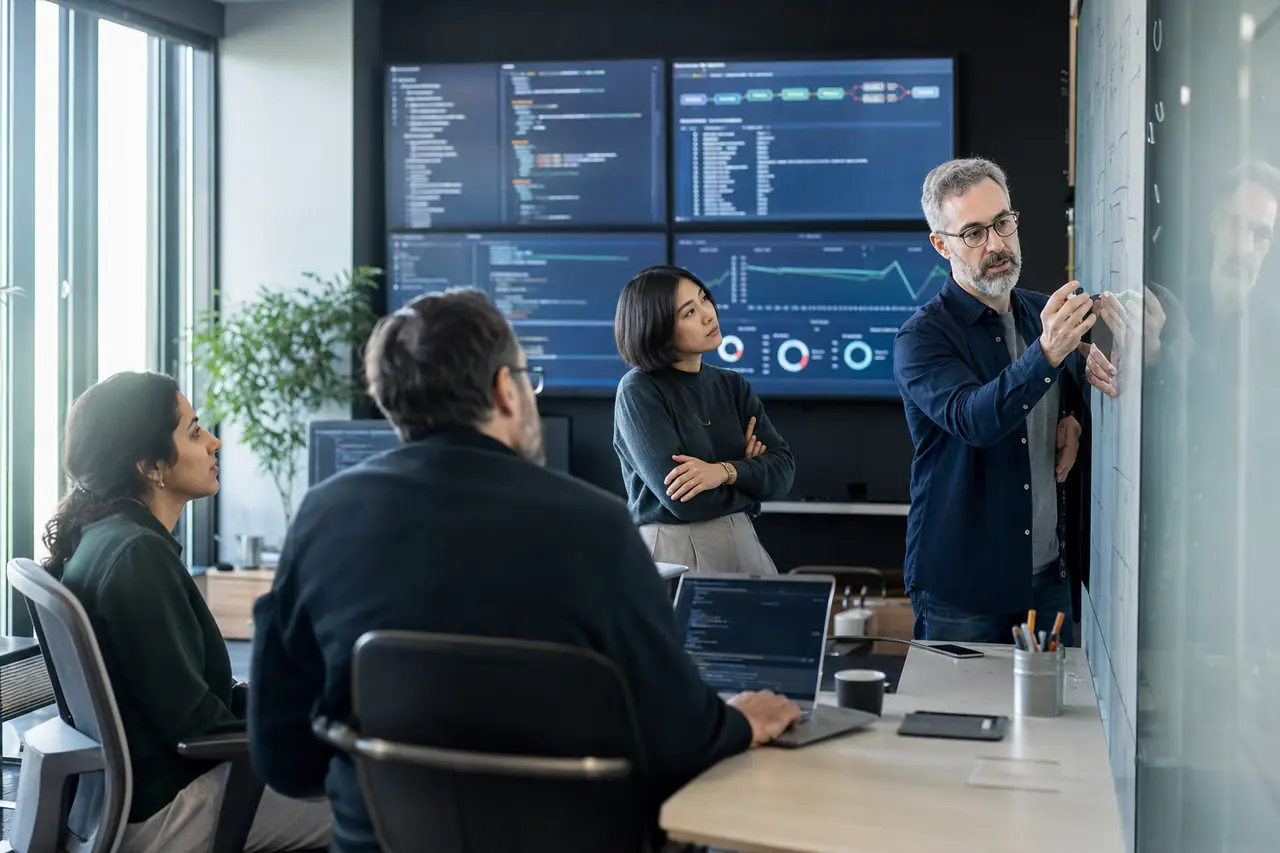 Engineers reviewing AI-assisted software delivery dashboards in a modern studio